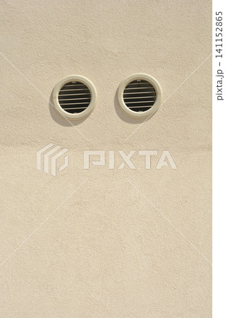 Two round ventilation grilles on a beige stucco wall background Two round ventilation grilles on a beige stucco wall background 141152865