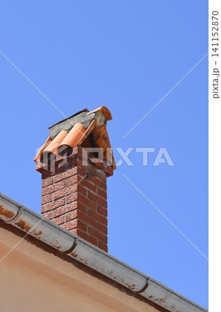 Brick chimney on a house roof against clear blue sky Brick chimney on a house roof against clear blue sky 141152870