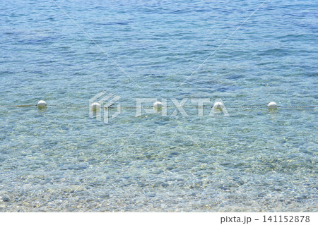 White buoys on a safety barrier rope in clear blue sea water White buoys on a safety barrier rope in clear blue sea water 141152878