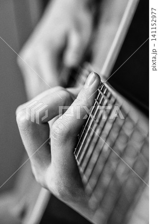 Woman hand playing six string acoustic guitar. Monochrome photo with retro style, noise and grain Woman hand playing six string acoustic guitar. Monochrome photo with retro style, noise and grain 141152977
