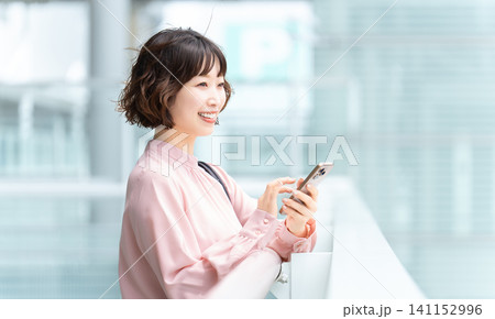 屋外でスマートフォンを使う女性・ビジネスウーマン 屋外でスマートフォンを使う女性・ビジネスウーマン 141152996