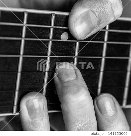 Musician hand playing guitar chord on fretboard. Monochrome photo with analog retro style effect Musician hand playing guitar chord on fretboard. Monochrome photo with analog retro style effect 141153003