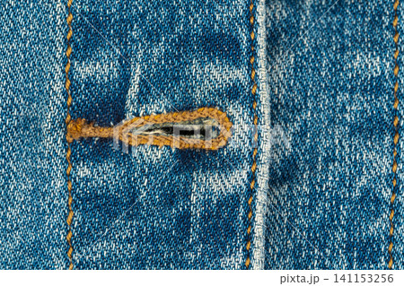 Blue denim fabric texture with buttonhole and orange stitching Blue denim fabric texture with buttonhole and orange stitching 141153256