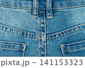 Blue jeans texture with back pocket detail. Close up of denim fabric with yellow stitching and belt loops 141153323