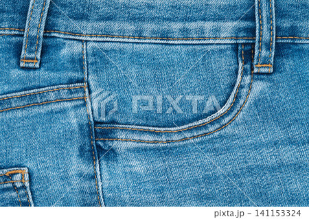 Blue denim jeans texture with front pocket and orange stitching detail Blue denim jeans texture with front pocket and orange stitching detail 141153324