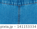 Blue denim fabric texture with symmetrical orange stitching and seam 141153334