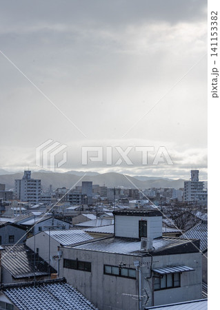 雪降る住宅街の屋根と遠くの山並み 雪降る住宅街の屋根と遠くの山並み 141153382