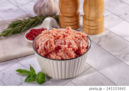 Raw minced chicken or turkey in a bowl with fresh herbs and spices on a kitchen counter Raw minced chicken or turkey in a bowl with fresh herbs and spices on a kitchen counter 141153842