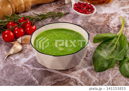 Green cream soup with fresh spinach, cherry tomatoes, and garlic on marble background Green cream soup with fresh spinach, cherry tomatoes, and garlic on marble background 141153853