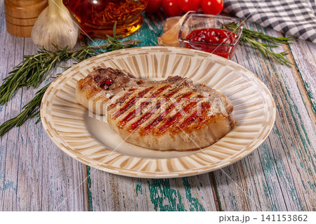 Grilled pork chop with pink peppercorns and rosemary on rustic wooden table Grilled pork chop with pink peppercorns and rosemary on rustic wooden table 141153862