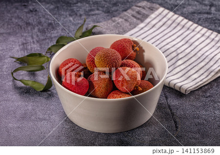 Fresh ripe lychee fruits in white bowl on dark textured background Fresh ripe lychee fruits in white bowl on dark textured background 141153869