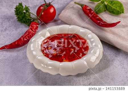Spicy red chili sauce in white ceramic bowl with fresh peppers and tomato Spicy red chili sauce in white ceramic bowl with fresh peppers and tomato 141153889