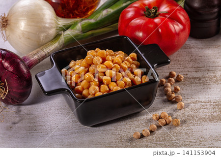 Cooked chickpeas in black ceramic bowl with fresh vegetables 141153904