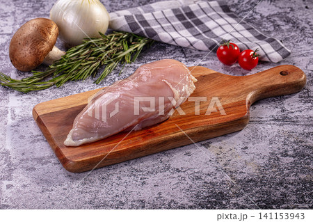 Raw chicken breast on wooden cutting board with rosemary mushroom onion and cherry tomatoes Raw chicken breast on wooden cutting board with rosemary mushroom onion and cherry tomatoes 141153943
