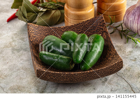 Fresh green jalapeno peppers in wooden bowl with herbs and spices 141155445