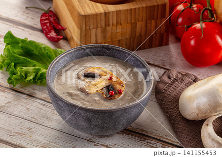Creamy mushroom soup in rustic bowl with fresh ingredients on wooden table Creamy mushroom soup in rustic bowl with fresh ingredients on wooden table 141155453