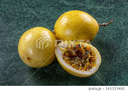 Yellow passion fruit whole and sliced on dark green textured surface 141155491