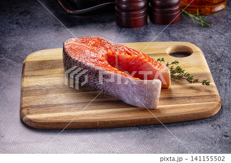 Fresh salmon fillet on wooden cutting board with herbs 141155502