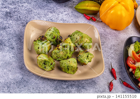 Mint chicken tikka pieces on beige plate with chili peppers and yellow pepper Mint chicken tikka pieces on beige plate with chili peppers and yellow pepper 141155510