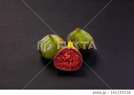 Fresh figs with vibrant red interior on dark textured background 141155516