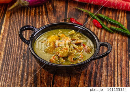 Green curry with shrimp in black bowl on wooden table Green curry with shrimp in black bowl on wooden table 141155524