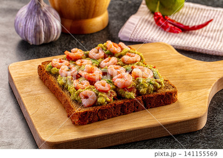 Shrimp avocado toast on wooden board with garlic and chili Shrimp avocado toast on wooden board with garlic and chili 141155569