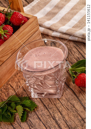 Strawberry smoothie in glass with fresh berries on wooden table Strawberry smoothie in glass with fresh berries on wooden table 141155612