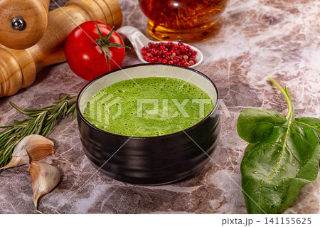 Green vegetable soup in black bowl with fresh spinach tomato and herbs on marble 141155625