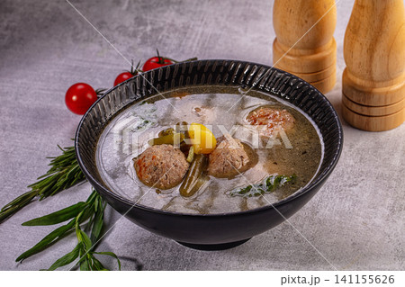 Meatball soup with vegetables in black ceramic bowl 141155626