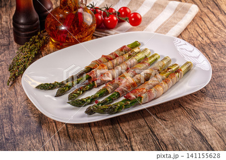 Bacon wrapped asparagus on white plate with cherry tomatoes and herbs 141155628