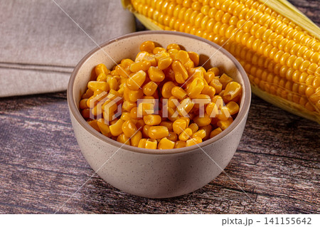 Bowl of fresh corn kernels with whole ear on wooden table 141155642