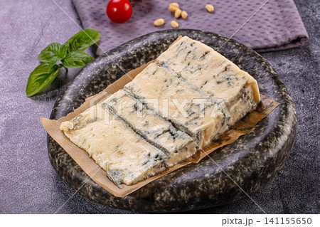 Gorgonzola cheese block on plate with basil and tomato 141155650