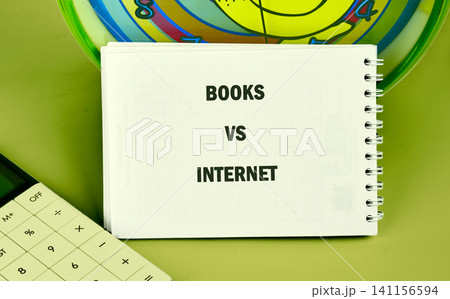 Two topics are compared in a study area with a spiral notebook showing titles about books and internet along with a calculator and clock on the table 141156594