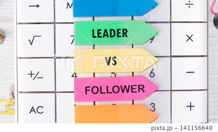 Colored arrows show the terms leader and follower in a workspace. The setting includes a calculator and office supplies, suggesting a focus on work and organization Colored arrows show the terms leader and follower in a workspace. The setting includes a calculator and office supplies, suggesting a focus on work and organization 141156640