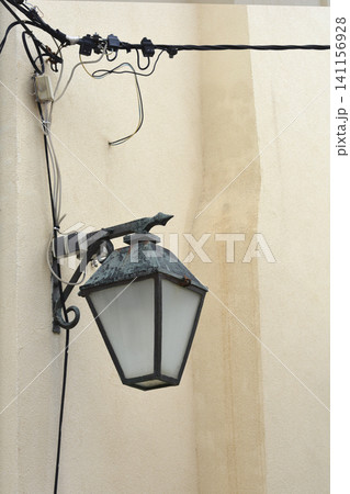 Vintage street lamp mounted on a wall with overhead wiring. Vintage street lamp mounted on a wall with overhead wiring. 141156928