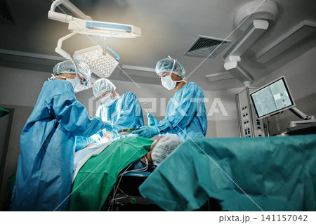 Healthcare, surgery and doctors with patient for emergency medical procedure in theater. Hospital, lights and surgical team for operation on person together in ICU, professional support and help. Healthcare, surgery and doctors with patient for emergency medical procedure in theater. Hospital, lights and surgical team for operation on person together in ICU, professional support and help. 141157042