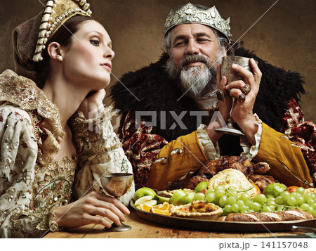 King, queen and feast with wine at table for fine dinning in royal banquet, vintage and majestic with crown. Monarch, husband and bored together with alcohol and buffet for formal celebration King, queen and feast with wine at table for fine dinning in royal banquet, vintage and majestic with crown. Monarch, husband and bored together with alcohol and buffet for formal celebration 141157048