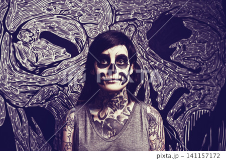 Skull, makeup and portrait of woman with pattern for festival, Halloween and day of the dead. Creative, costume and person with face paint for horror, scary and gothic aesthetic in studio background 141157172