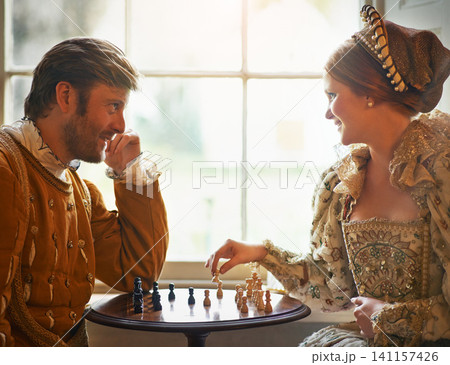 Renaissance, couple and chess at home with smile, vintage and medieval costume in a palace. Window, luxury and queen together with smile from strategy game and talking while playing with love Renaissance, couple and chess at home with smile, vintage and medieval costume in a palace. Window, luxury and queen together with smile from strategy game and talking while playing with love 141157426