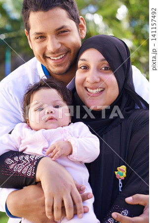 Muslim, park and portrait of parents with baby for bonding, ramadan and outdoors together. Islam, happy family and mother, father and newborn infant for love, childcare and support in garden 141157492
