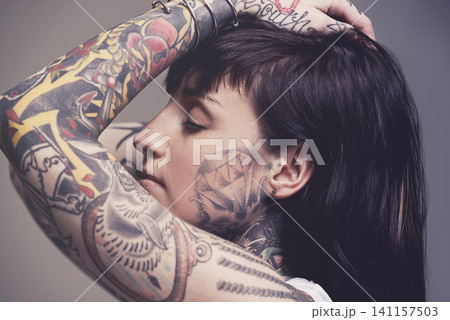 Tattoo, culture and rebel with woman, punk rock and tradition on a grey studio background. Profile, person and model with ideas and creativity with cool gothic art with ink, trendy and edgy design Tattoo, culture and rebel with woman, punk rock and tradition on a grey studio background. Profile, person and model with ideas and creativity with cool gothic art with ink, trendy and edgy design 141157503
