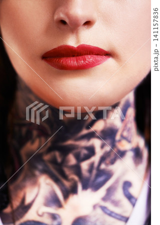 Closeup, red lipstick and woman with tattoos, makeup and culture with rebel and confident. Person, mouth and product with ink and artistic with tradition and design with pattern and shine with glow Closeup, red lipstick and woman with tattoos, makeup and culture with rebel and confident. Person, mouth and product with ink and artistic with tradition and design with pattern and shine with glow 141157836