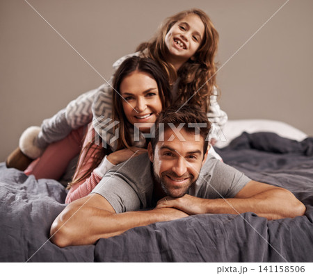 Parents, child and portrait in bedroom to relax in home for weekend break, family time and happiness for bonding. Father, mother and girl comfy or cozy together on Easter Sunday morning for love. 141158506