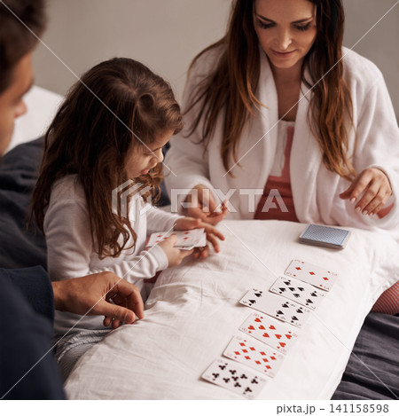 Mom, father and girl with playing cards for game with bonding, learning and relax with strategy in bedroom. Dad, mother and daughter with deal, deck and child on bed with connection in family house Mom, father and girl with playing cards for game with bonding, learning and relax with strategy in bedroom. Dad, mother and daughter with deal, deck and child on bed with connection in family house 141158598