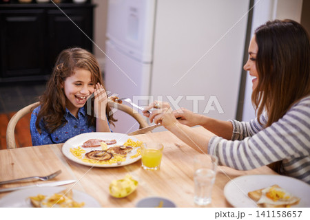Mom, child and laugh in morning with breakfast for routine with quality time, happiness and nutrition. Mother, girl and together for bonding with food, feeding and homemade with love for healthy diet Mom, child and laugh in morning with breakfast for routine with quality time, happiness and nutrition. Mother, girl and together for bonding with food, feeding and homemade with love for healthy diet 141158657
