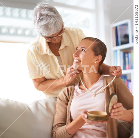 Senior mother, daughter and necklace for gift on sofa with family inheritance, smile or love in lounge. Elderly mom, person and pearl jewelry for present, vintage style or culture on couch in home Senior mother, daughter and necklace for gift on sofa with family inheritance, smile or love in lounge. Elderly mom, person and pearl jewelry for present, vintage style or culture on couch in home 141158672