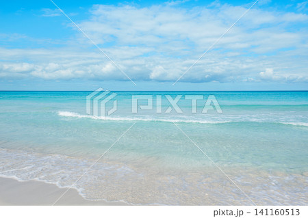 Calm ocean waves gently lap on the sandy shore under a bright blue sky Calm ocean waves gently lap on the sandy shore under a bright blue sky 141160513