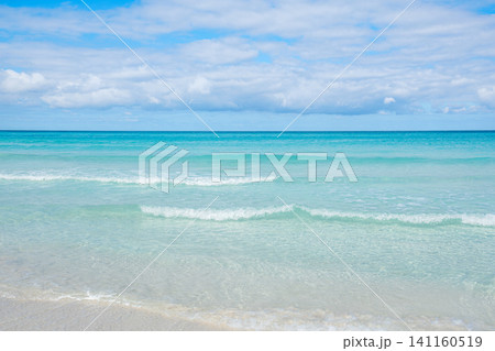 Calm ocean waves gently lap on the sandy shore under a bright blue sky Calm ocean waves gently lap on the sandy shore under a bright blue sky 141160519