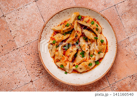 Dumplings with spicy sauce served on a plate 141160540