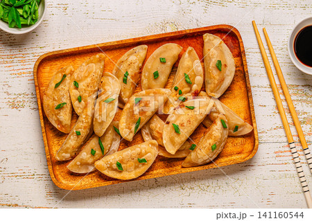 Dumplings on a wooden plate with chopsticks and soy sauce 141160544